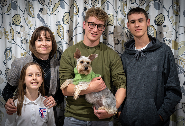 Damian posing for a family photo with his Auckland host family and the family dog