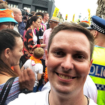 Yury in Auckland street with New Zealand Prime Minister Jacinda Ardern and a crowd in the background